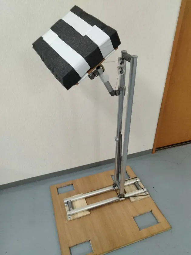 木製のベース上にアルミフレームで組み立てられた機械装置の試作機が写っています。