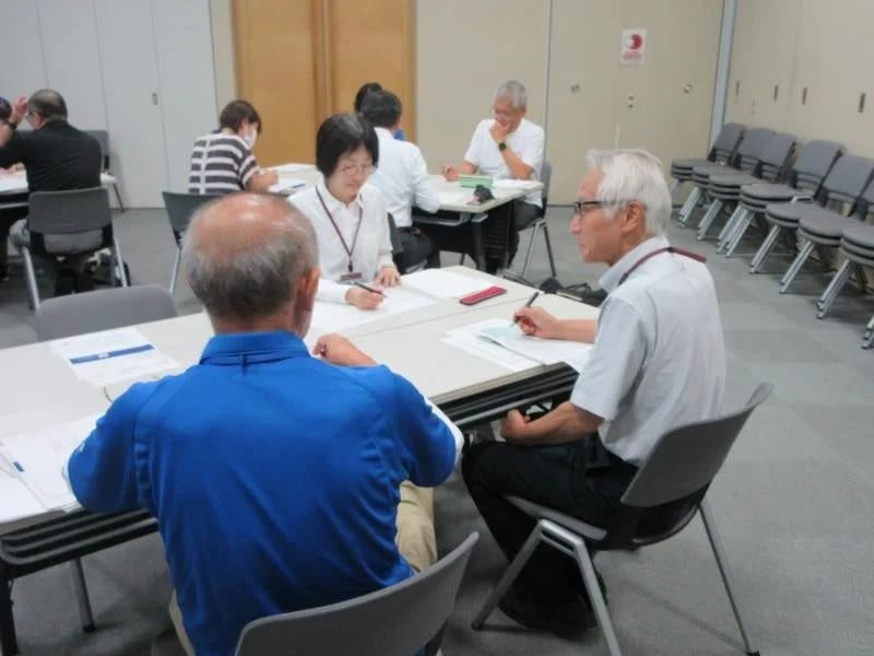 会議室で資料を見ながら話し合う参加者
